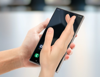 A hand performing a palm swipe gesture on a Galaxy phone to capture a screenshot.