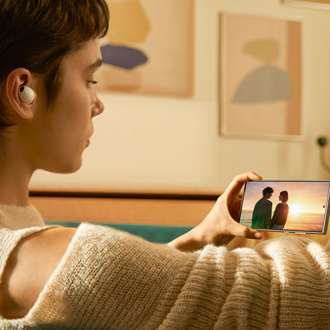 Woman viewing a video on a Galaxy S24 Ultra and wearing Galaxy Buds2 Pro