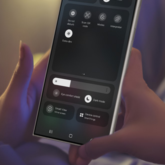 Hand holding a Galaxy phone while displaying the Extra dim button on the Quick settings panel