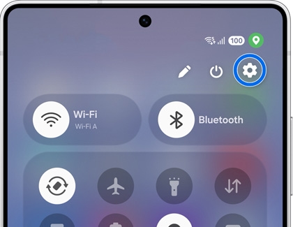 A Galaxy S25 showing the quick settings panel with a blue circle highlighting the settings gear icon in the top right corner.