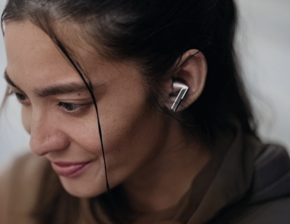 Person wearing Galaxy Buds3 Pro, smiling while listening to audio.