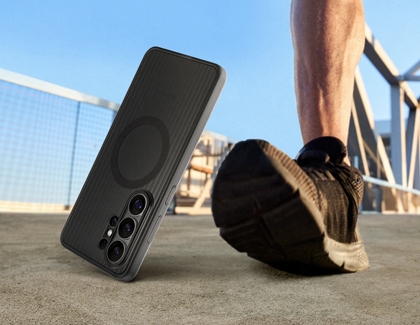 A black Galaxy S26 Ultra in a rugged case, standing on a concrete surface near a person running.
