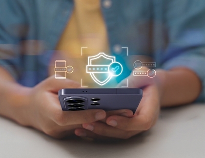 A person holding a purple Galaxy S26 phone with digital security graphics floating above the screen.