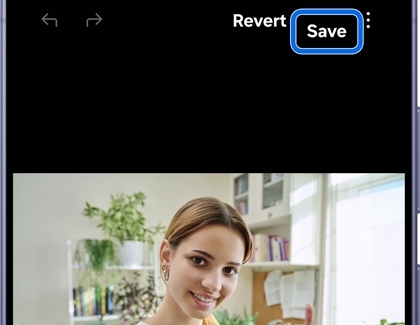 A Galaxy phone showing a photo of a smiling woman in an office setting with Revert and Save options at the top, Save highlighted in blue.