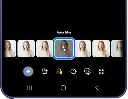 A Galaxy phone showing the Gallery editor with Aura film filter selected and highlighted in blue in a row of filter previews of a woman's photo.