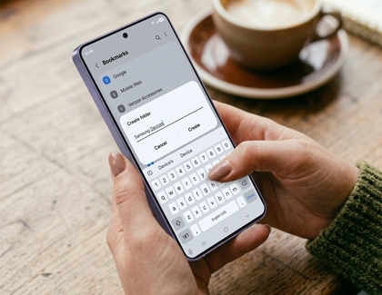 A person holding a purple Galaxy S26 phone and typing on the keyboard to create a new folder under bookmarks.
