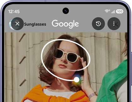 A Galaxy S26 Ultra screen showing a white circle drawn around a woman wearing sunglasses to initiate a search.