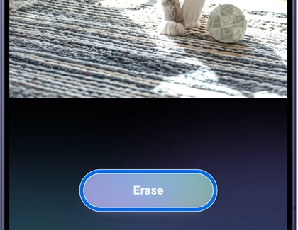 A Galaxy S26 phone showing the photo assist screen with an Erase button highlighted in blue below an image of a cat paws on a rug.