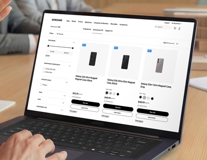 A person using a laptop to browse the Samsung website, displaying several black Galaxy S26 cases for sale.