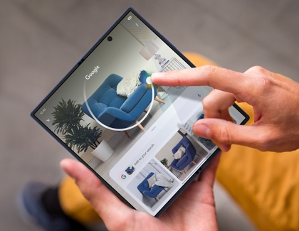 Person using Circle to Search on a Galaxy Z Fold7 to identify a blue couch within a living room image.