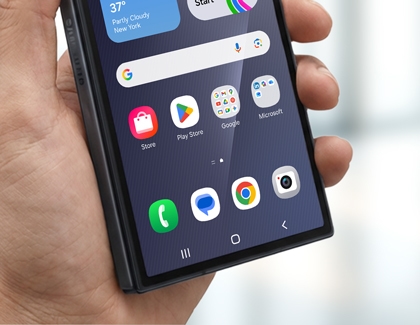 Hands holding the Galaxy Z TriFold cover screen with the Camera app icon visible.