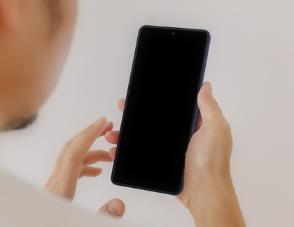 Person holding a Galaxy Z Flip7 with the screen off, preparing to power on the device for the first time.