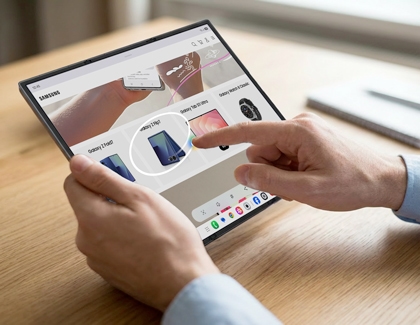 A finger touching a screen displaying a product image inside a white circle on the unfolded Galaxy Z TriFold screen.