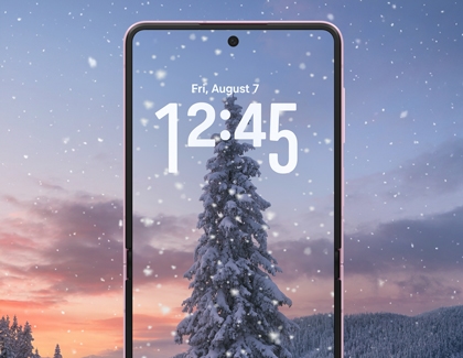 A Galaxy Z Flip showing a lock screen with falling snow over a snowy tree background.