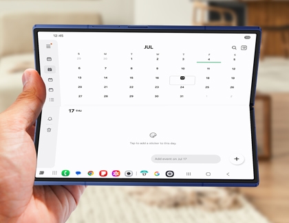 Person holding the Galaxy Z Fold7 opened in tablet mode while viewing the Calendar app in a living room.