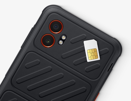 A SIM card resting on the back panel of a rugged black Galaxy XCover phone.