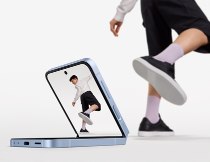 A man taking a picture of himself from a distance using Flex mode on a Galaxy Z Flip6 while placed on the floor