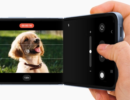 Close-up of a Samsung Galaxy Z Flip6 phone in Flex mode, capturing a video of a puppy with the camera app's controls visible on the right screen