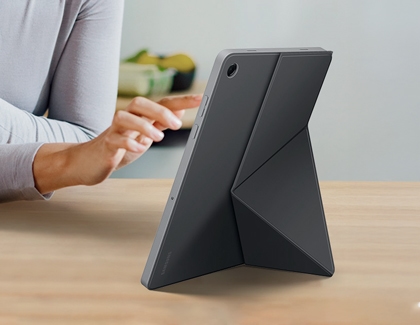 Person touching the screen of a Galaxy Tab A11 Plus supported by a gray origami style book cover