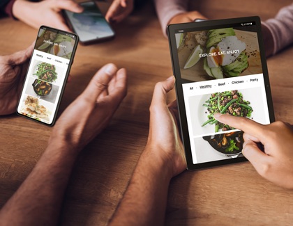 Galaxy S21 and Galaxy Tab A8 displaying the same recipe app, with a hand tapping on a dish to continue browsing.