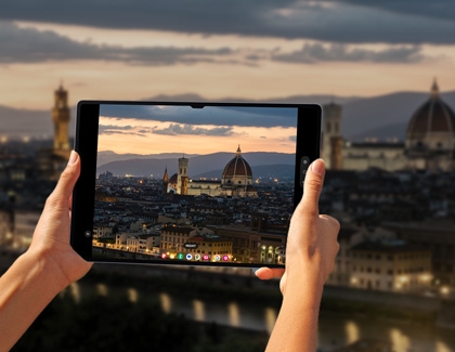 A person using a Galaxy tablet to take a picture of the sunset while using Night mode