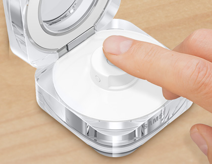 A finger pressing and holding the multipurpose button on the Galaxy Ring charging case.