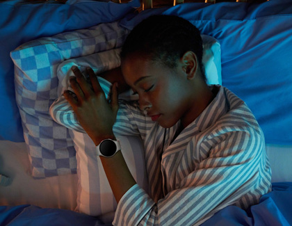 A girl sleeping in bed while wearing a Galaxy Watch