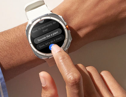 A person interacting with a Galaxy Watch7, selecting a quick reply message on the display.