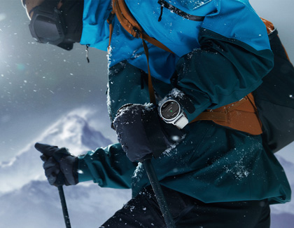 A person skiing in the snow, wearing a Galaxy Watch7 on their wrist.