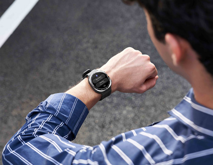 A man standing outdoors, looking at his Galaxy Watch7, ready to make or receive a call.