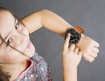 A child smiling and interacting with a Galaxy Watch7 on their wrist.