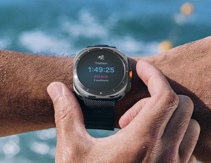 A person wearing a Galaxy Watch7 near the beach, showing a triathlon tracking screen with time and calories burned.