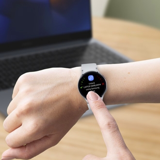 Person using Samsung Flow on a Galaxy Watch to unlock a laptop