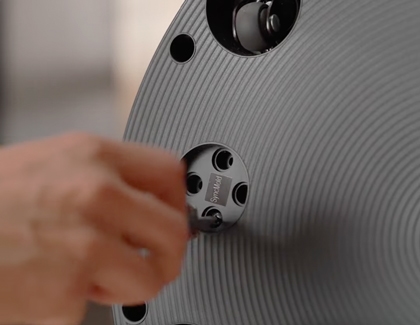 Hand tightening a mounting screw on the back of the Samsung MovingStyle stand base.