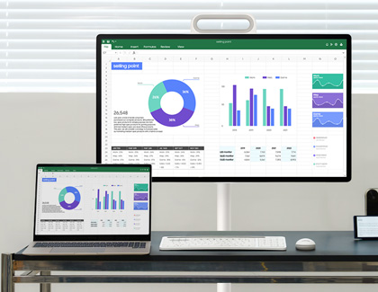 MovingStyle and a laptop side-by-side on a desk both displaying the same spreadsheet data.