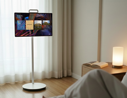 MovingStyle TV on a white floor stand in a room with a lamp and open book on a side table.