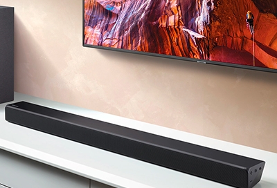 Soundbar sitting on a table in front of a mounted Samsung TV