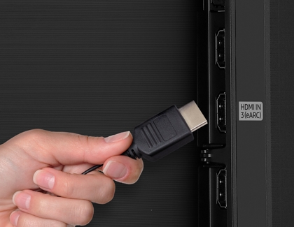 A hand plugging an HDMI cable into a Samsung TV port labeled HDMI IN 3 (eARC).