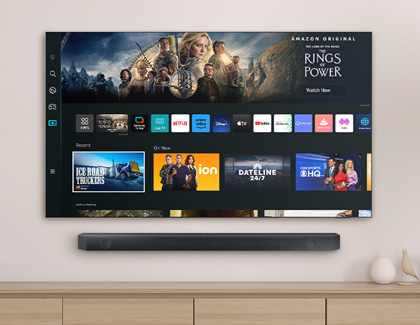 Samsung TV displaying the home screen with various apps and content and a soundbar mounted below the TV.