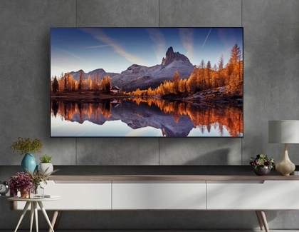 Samsung TV mounted on a concrete wall above a console table displaying a mountain landscape.