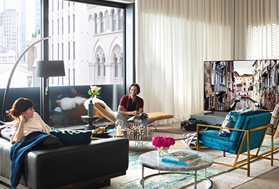 Two people in a living room watching a Samsung QLED TV