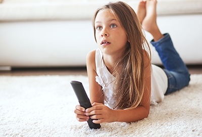 Little girl watching TV while laying on the floor