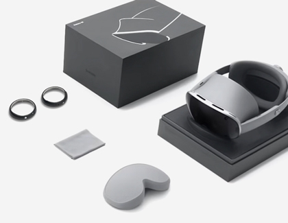 Galaxy XR headset and included accessories arranged on a table, including two lens inserts, a cleaning cloth, and a face pad.