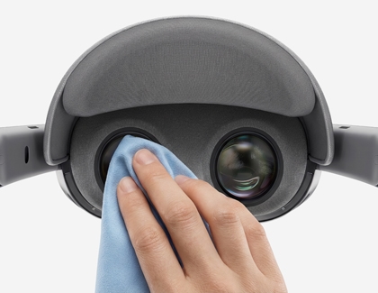 A hand wiping the Galaxy XR headset lenses with a soft microfiber cloth.