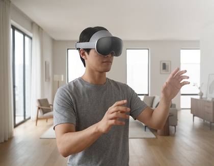 A person wearing the Galaxy XR headset indoors with both hands raised for gesture input.