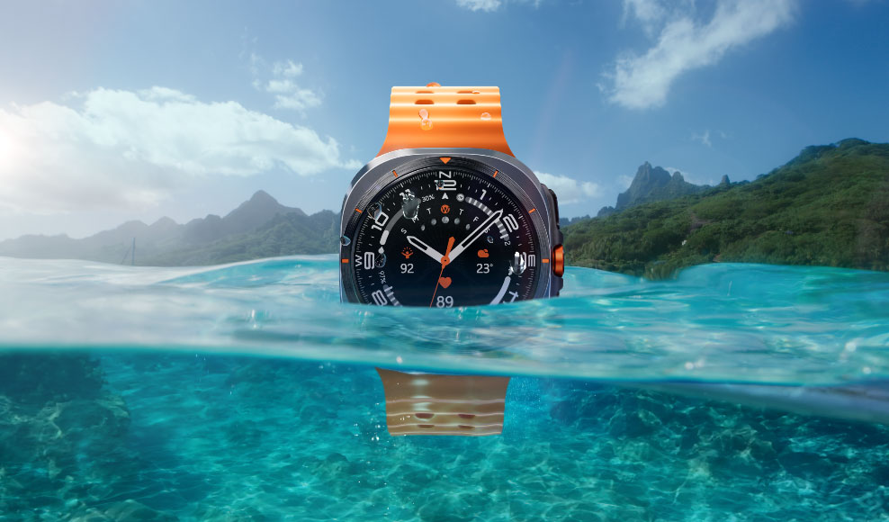 A Galaxy Watch Ultra is seen half-submerged in the moving ocean water with water droplets visible on the watch.