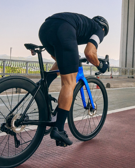 A man in cycling gear is riding a road race bike along a bike path.