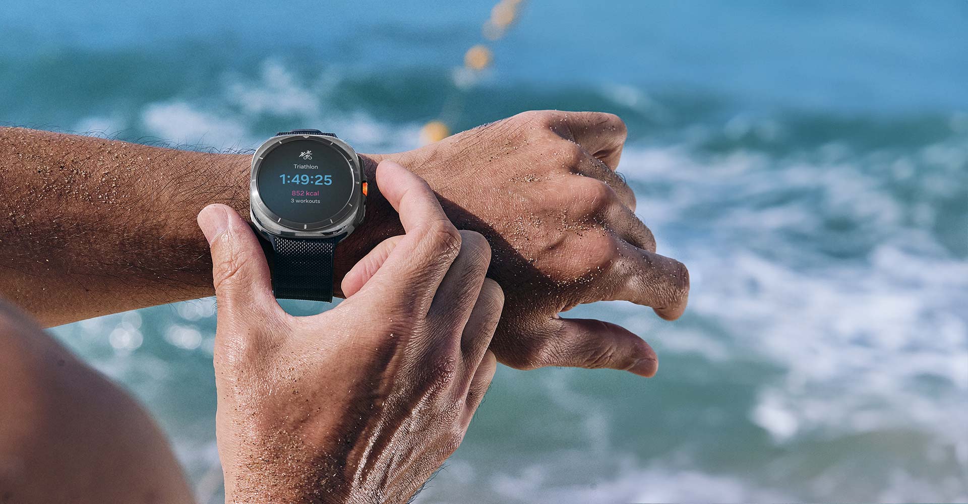 A hand is making a motion to press the Quick Button on a Galaxy Watch Ultra worn on the wrist. The Triathlon workout tracking screen is shown on the watch.