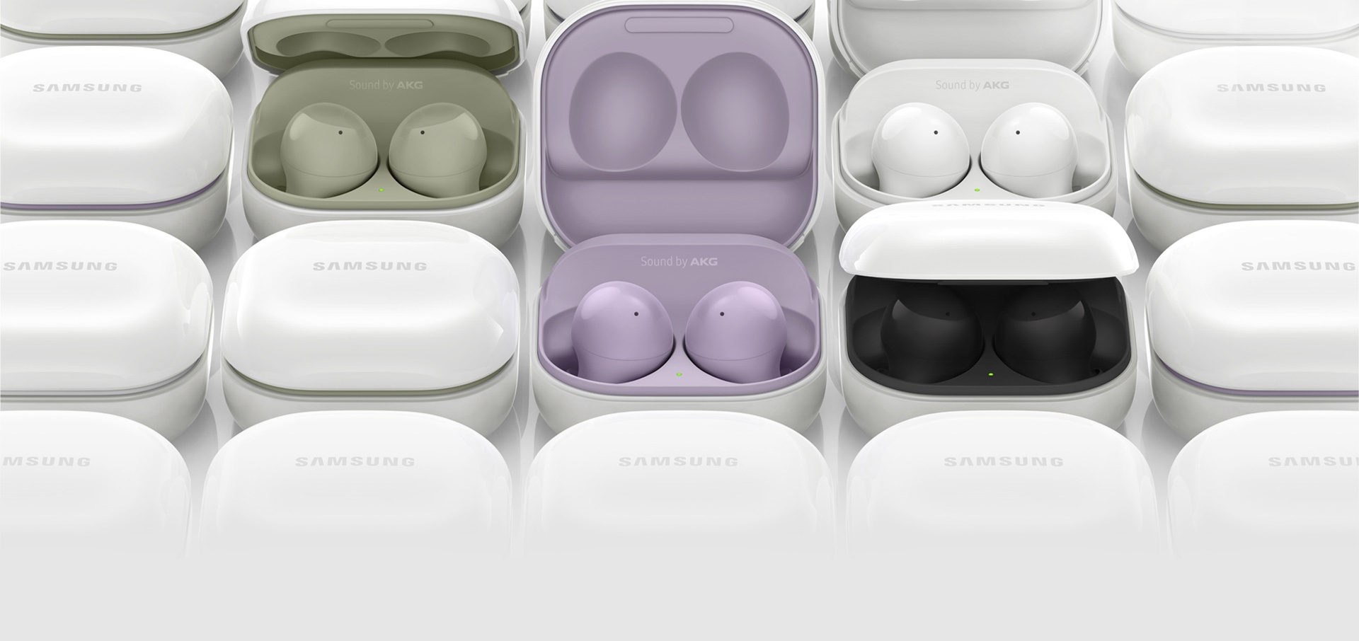 Galaxy Buds2 cases are placed next to each other. Several of the cases are opened, each showing different colors of the inside case, from olive green, lavender, white, to black.