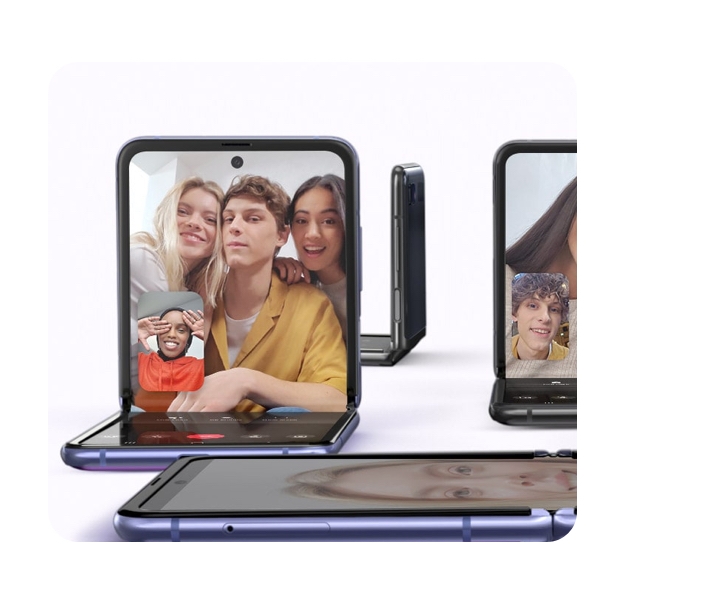 The Galaxy Z Flip is positioned in four diffeent angles. One is facing the viewer and shows a video conference going on. Three people are in the screen while another is in the lower eft hand corner. Another phone is laying flat, one is the background while another is cut off on the right. 